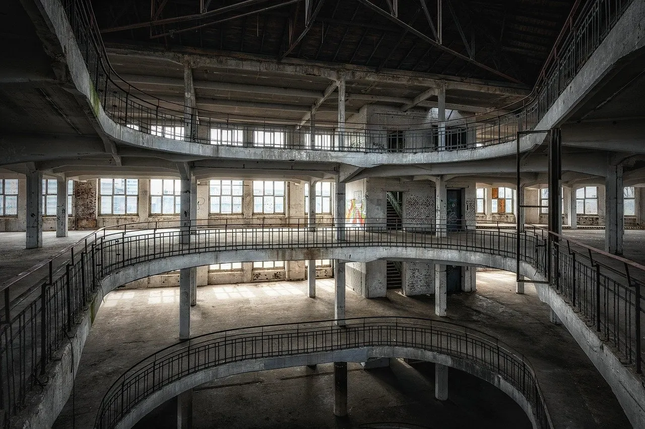 Mehrgeschossiges Gebäude mit geschwungenen Betonrampen, Geländern und großen Fensterreihen.