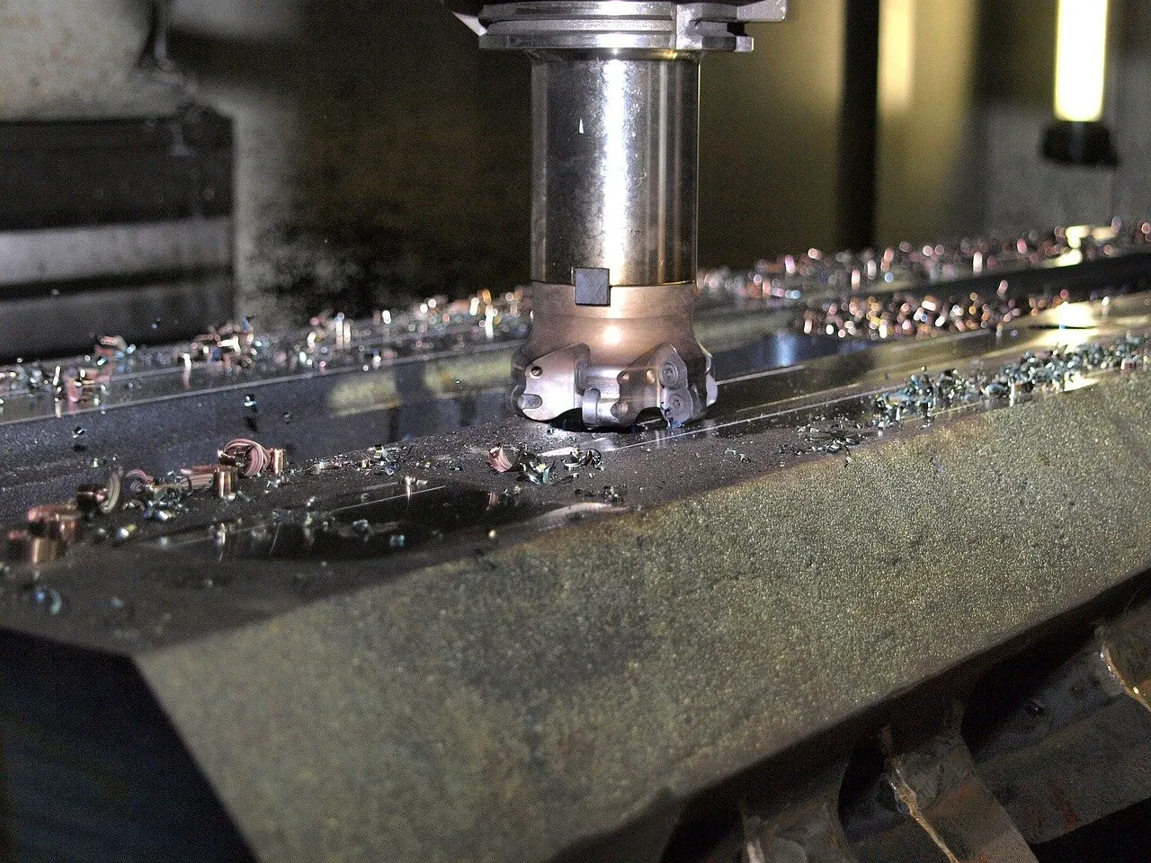 Planfräser bearbeitet eine Werkstückoberfläche, kleine Metallspäne liegen verteilt auf dem Werkstück.