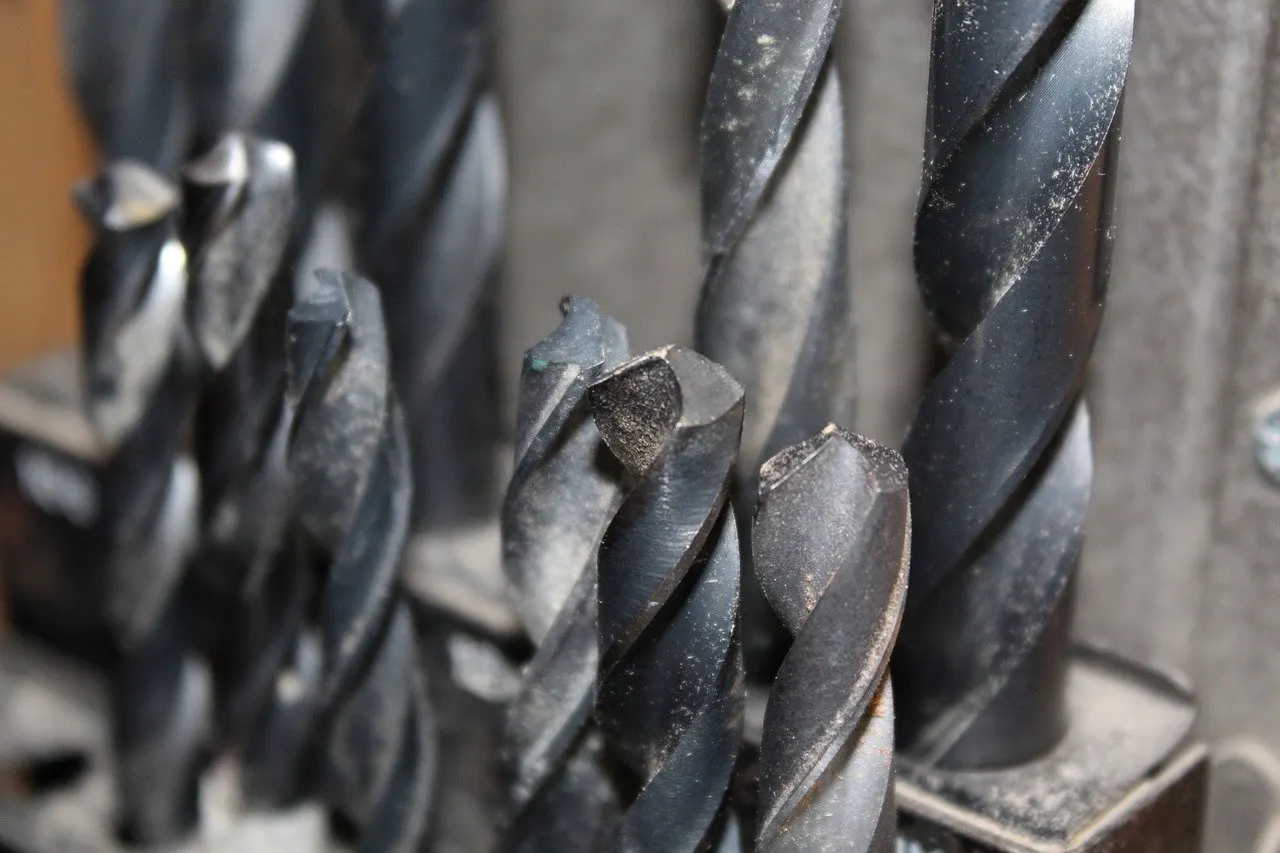 Mehrere Spiralbohrer aus Metall nebeneinander, Nahaufnahme mit unscharfem Hintergrund.