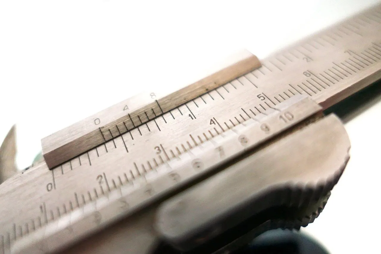 Nahaufnahme einer Schieblehre mit Messskalen in Millimeter und Zoll auf Metall.